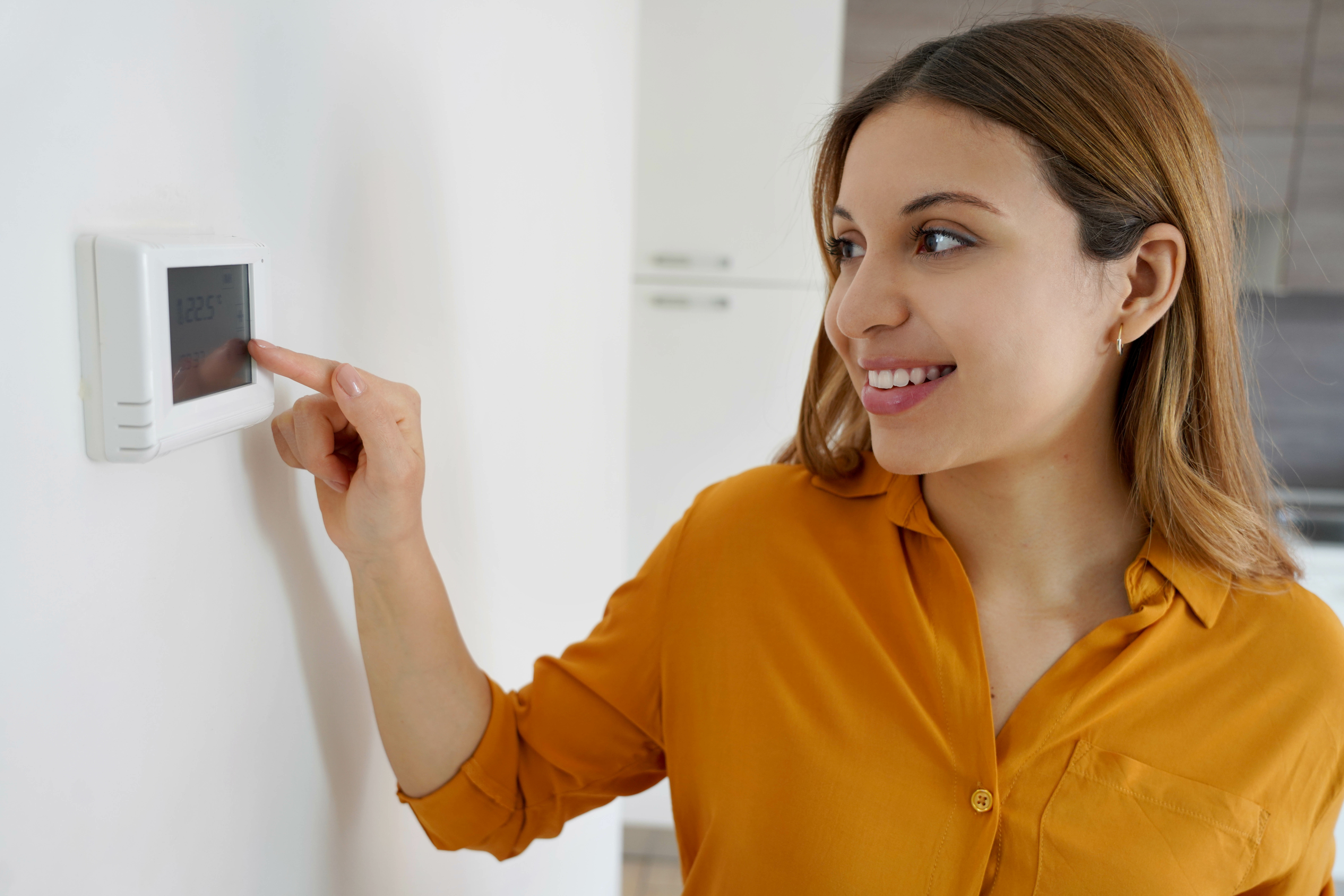 woman adjusting her digital thermostat