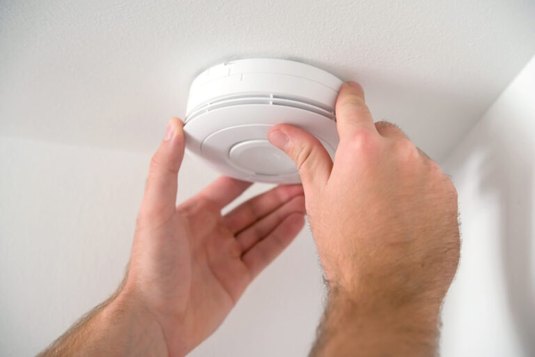 hands adjusting a carbon monoxide detector